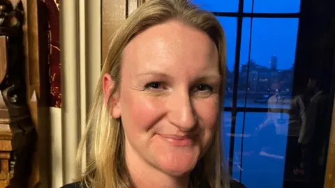 Dr Jess Garland in the Houses of Parliament with a window behind her with a view onto the River Thames