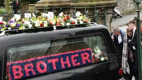Pacemaker Morgan Barnard's parents and brother walk behind the hearse carrying his coffin