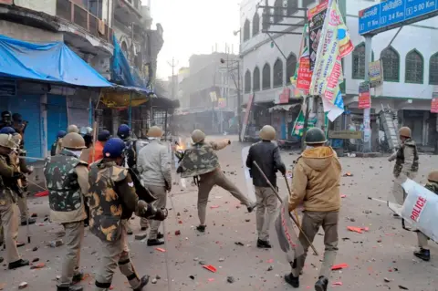 Getty Images A policeman throws stones towards protesters during demonstrations against India's new citizenship law in Kanpur on December 21, 2019.