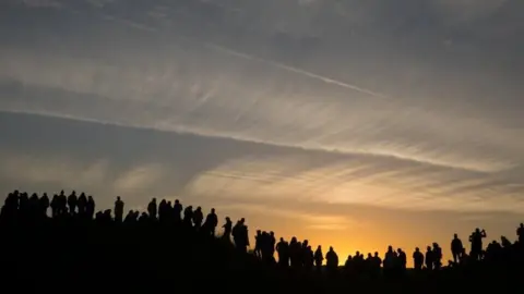 Getty Images People standing on hill watching sunrise