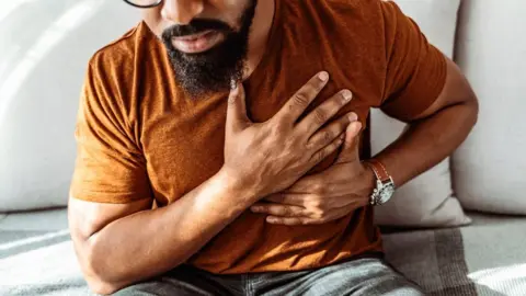 Getty Images Man holding his chest