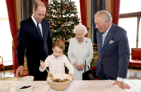 PA Media Queen Elizabeth II, the Prince of Wales, the Duke of Cambridge and Prince George preparing special Christmas puddings in the Music Room at Buckingham Palace, London, as part of the launch of The Royal British Legion"s Together at Christmas initiative