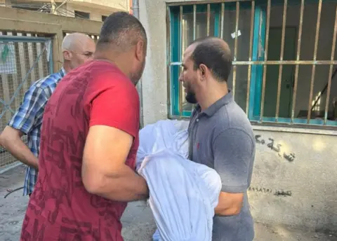 Moamen El Halabi wrapped body of Omar being carried away