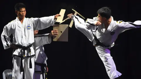 AFP/Getty A man kicks through a wooden board during a taekwondo demonstration