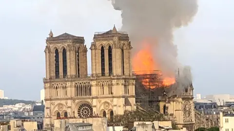 Marion LeBlanc Worher Flames billow from Notre-Dame cathedral in Paris