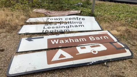 Scene of Stalham crash with damaged road sign on ground.