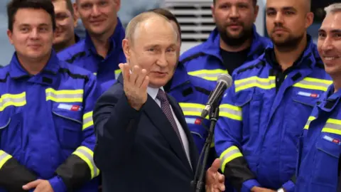 Getty Images Russian President Vladimir Putin (C) gestures during an opening ceremony of a gravity-type base for natural gas liquefaction at the Novatek-Murmansk's Offshore Superfacility Constrution Center for the construction of large-tonnage offshore stuctures (CSMCS) of Novatek company on July 20, 2023 in the villiage of Belokamenka outside Murmank, Russia