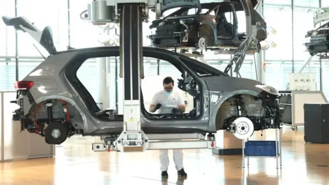 Sean Gallup A worker assembles the interior of a Volkswagen ID.3 electric car on the assembly line at the "Gläserne Manufaktur" ("Glass Manufactory") production facility on June 08, 2021 in Dresden, Germany.