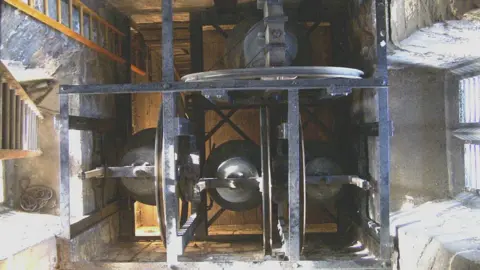 Ray Gambell The top of four church bells hanging down in a church tower, Landbeach