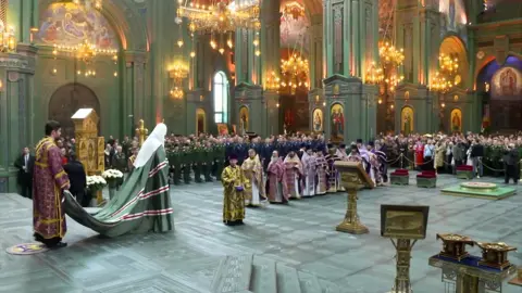 Russian Orthodox Church Patriarch Kirill, in green robes, at a service attended military personnel