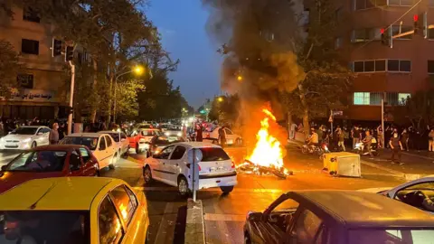 Reuters File photo showing a police motorcycle on fire during a protest over the death of Mahsa Amini in Tehran, Iran (19 September 2022)