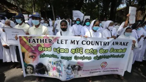 EPA Catholic nuns hold up a banner reading 'Father, Let my country awake' at a protest in Colombo against the government's handling of the economic crisis