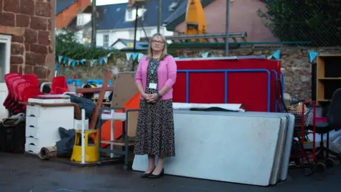 Woman stood by pile of damaged school items