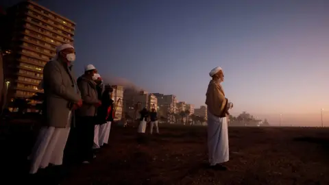 Mike Hutchings/Reuters A group of Muslim clerics below a dark sky with buildings in the distance