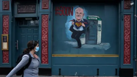 Reuters Woman walks past a closed pub in Dublin