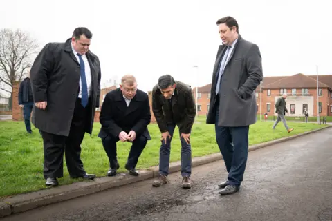 PA Media Rishi Sunak inspecting a pothole in Darlington with local politicians