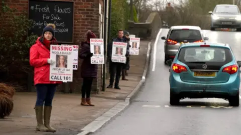 PA Media People hold missing person appeal posters on road in St Michael's on Wyre, Lancashire