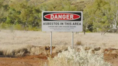 WESTERN AUSTRALIA GOVERNMENT A warning sign around Wittenoom which reads: Danger. Asbestos in this area. Cancer and Lung disease hazard