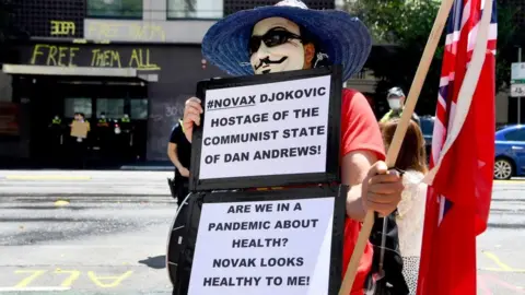 Getty Images An anti-vax protester holds a sign supporting Novak Djokovic