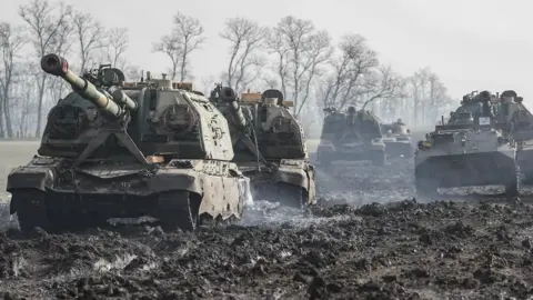 EPA A tank and other armoured vehicles sit on a mud road