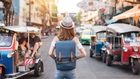 Getty Images The back of a young woman walking in Bangkok