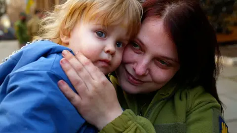 Fred Scott/BBC Katrine the sniper cuddles her son before heading off to fight