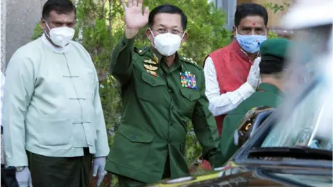 Getty Images Myanmar's commander-in-chief Senior General Min Aung Hlaing waves to journalists after visiting the Sri Sri Durga Bari Hindu temple in Yangon