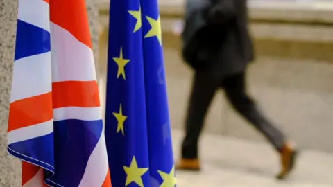 Getty Images Man rushes by UK and EU flags
