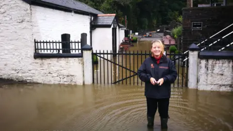 Phillip Jones Woman standing in flood water in Aberdulais