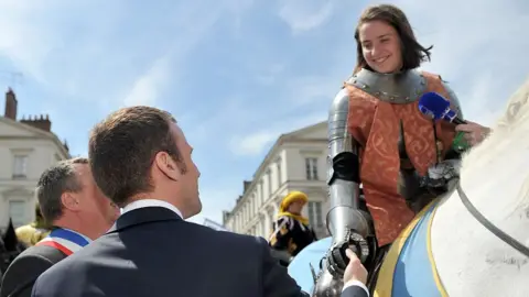 Getty Images Macro shakes hands with Joan of Arc impersonator in 2016.