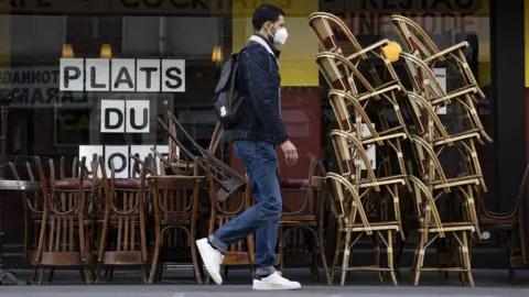 EPA A man walks by an empty cafe in Paris