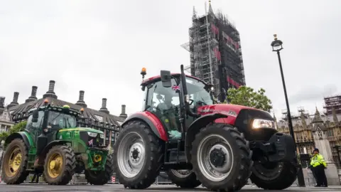 Getty Images Farmers drive their tractors past the Houses of Parliament, watched by policemen