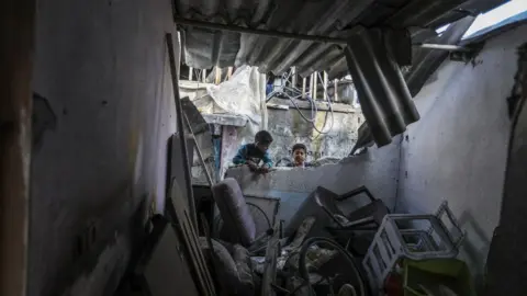 Getty Images Two children collect belongings from a destroyed home in Rafah, southern Gaza on 1 April