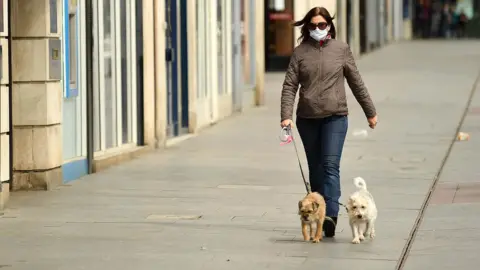 Getty Images A woman walks two dogs in an empty street