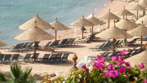 Getty Images Beach with umbrellas with some flowers in the foreground