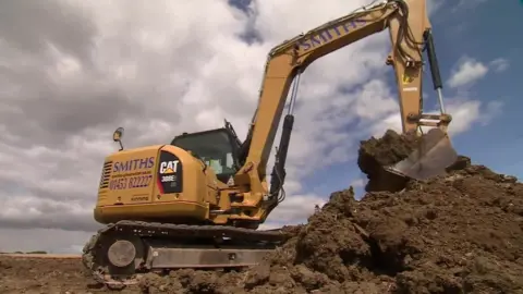 BBC JCB digging a trench and earth bank at a farm