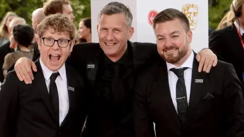 Getty Images The Last Leg stars Josh Widdicombe, Adam Hills and Alex Brooker at the Bafta TV Awards in 2018