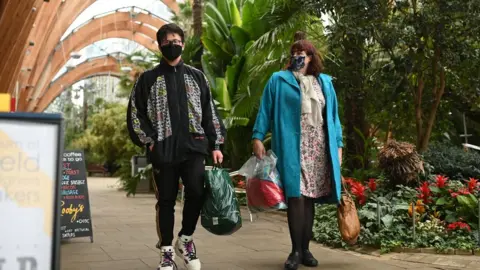 Getty Images A couple wearing protective face masks, walk through The Winter Garden in Sheffield, in northern England on October 21, 2020