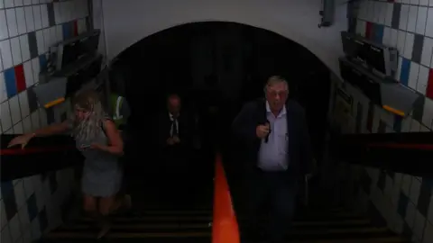 PA Media People walking through Clapham Junction station in London during a power cut