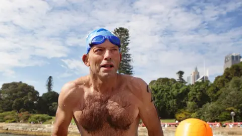 Getty Images Tony Abbott in a swimming cap and swimmers in a charity swim in 2010