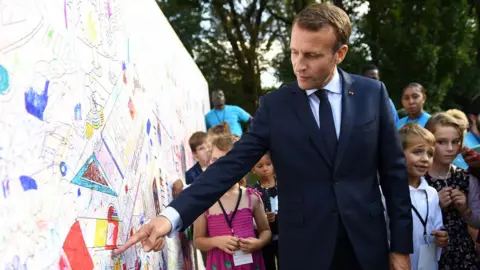 Getty Images French President Emmanuel Macron looks at a wall with children's drawings as visitors are allowed access to the Elysee Palace in Paris on September 15, 2018