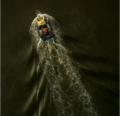 Michael Marsh An aerial shot of a fishing boat leaving a trail of disturbance in the water