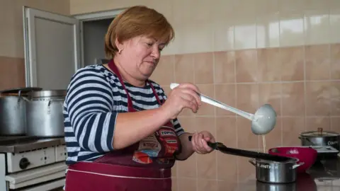 A woman in Komyshuvakha making pancakes