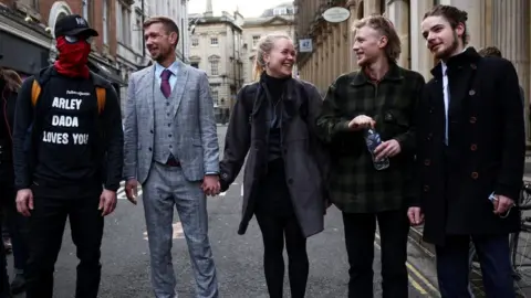 Reuters From l-r Jake Skuse (in a mask), a friend in a grey checked suit, Rhian Graham, Milo Ponsford, and Sage Willoughby arrived at court together