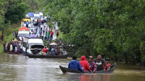 Reuters Two boats carrying men float on a lake in Madagascar as several vans and people look on. The chaos was cause by tropical storm Eliakim near Manambonitra, Atsinanana region, Madagascar.