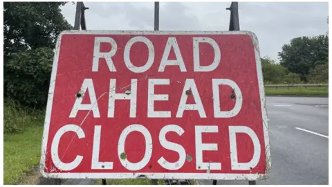 BBC A close-up photo of a red 'Road Ahead Closed' sign