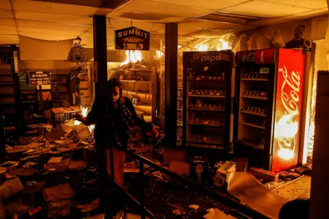 Reuters A woman reacts while protesters set fire in a liquor store