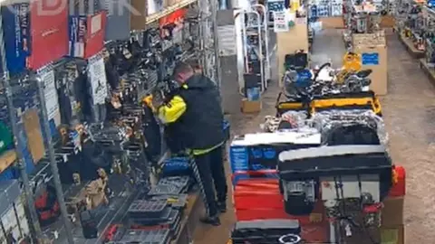 Mackays of Cambridge Man shown putting tools into his jacket at Mackays, Cambridge