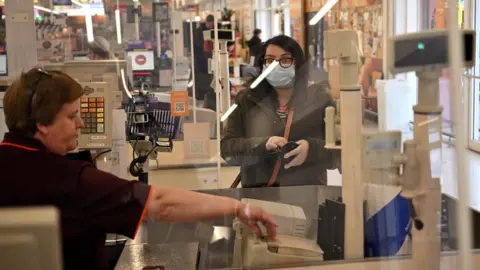 Getty Images A supermarket worker behind a protective screen