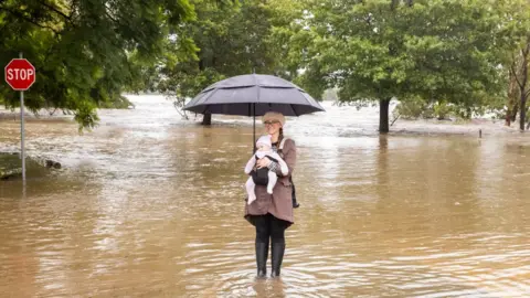 Getty Images Woman and baby take photo in flood
